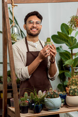 Smiling male flower shop assistant showing a small cactus