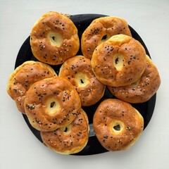 Plate of freshly baked homemade cottage cheese bagels topped with black and white sesame seeds. Golden crust and soft texture make them perfect for breakfast or snack.