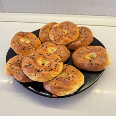 Plate of freshly baked homemade cottage cheese bagels topped with black and white sesame seeds. Golden crust and soft texture make them perfect for breakfast or snack.