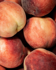 Close-up of fresh ripe peaches with fuzzy skin in warm red and yellow tones. Perfect for food, summer, and healthy lifestyle themes.