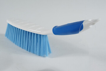 Hard bristle cleaning brush with long blue handle and ergonomic gray grip, isolated on white...