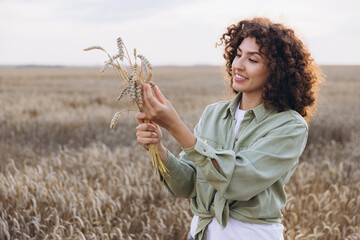 Agronomist woman holding wheat ears in golden field