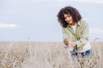 Agronomist woman inspecting wheat ears in cultivated field