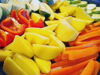 Sliced vegetables, potatoes, peppers, carrots and squash on a baking sheet ready for baking....