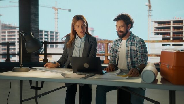 Architect and engineer discussing project on laptop in construction site office