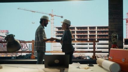 Construction workers shaking hands at construction site: celebrating successful partnership