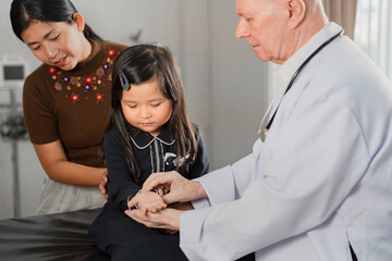 Caucasian Doctor check Asia kid girl patience's pulse by fingers with assistant at hospital