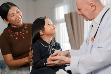 Caucasian Doctor check Asia kid girl patience's pulse by fingers with assistant at hospital