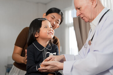 Caucasian Doctor check Asia kid girl patience's pulse by fingers with assistant at hospital