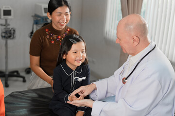Caucasian Doctor check Asia kid girl patience's pulse by fingers with assistant at hospital
