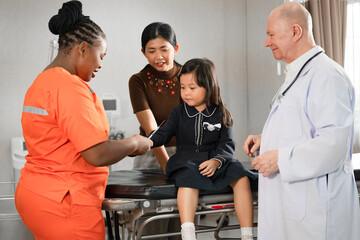 Nurse with doctor giving vaccine to Asia kid girl with assistant at hospital