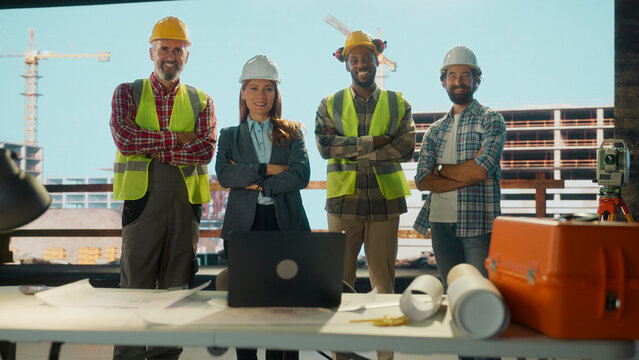 Team of architects and engineers smiling with arms crossed in their office on construction site