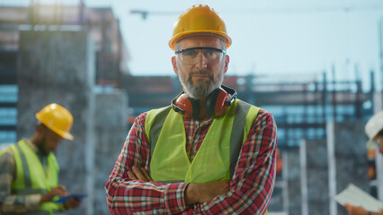 Confident construction worker posing at building site with crossed arms