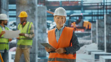 Female engineer smiling and holding tablet at construction site