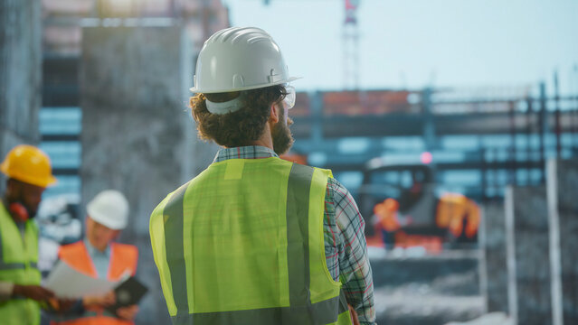 Construction supervisor overseeing building operations at site with team discussing blueprints