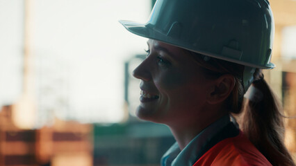 Female engineer smiling and wearing hardhat on construction site