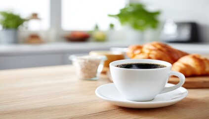 Obraz premium Simple Breakfast Still Life. Cup of black coffee on a saucer sits on a wooden table with croissants, oatmeal in a jar, and blurred kitchen background with plants and window