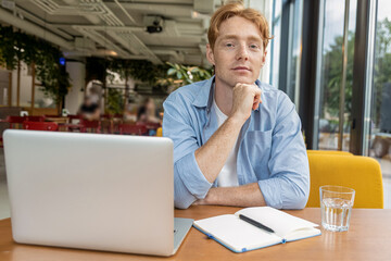 Ginger young man sitting at the table in the cafe