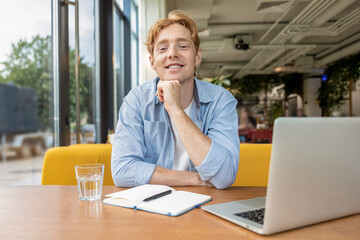 Ginger young man sitting at the table in the cafe