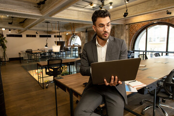 Young man with laptop looking surprised and emotional