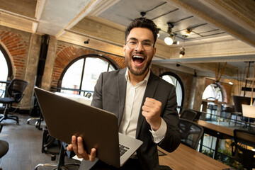 Caucasian young man in the office looking excited and happy