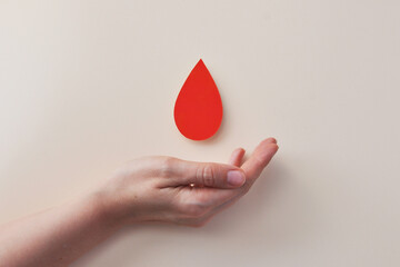 Hand holding a blood drop symbol representing donation or medical awareness.