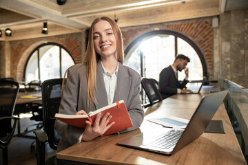 Pretty young woman sitting in the office at the laptop
