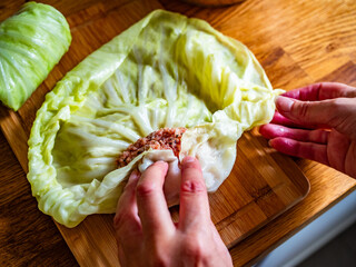 Cooking stuffed cabbages on wooden table - polish cuisine golabki