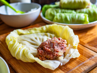 Cooking stuffed cabbages on wooden table - polish cuisine golabki