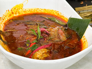 Red snapper in spicy, sourm tangy broth, garnished with herbs and chili, a bold traditional Malaysian dish known as Asam Pedas Ikan Merah.

