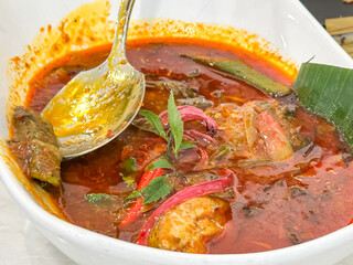 Red snapper in spicy, sourm tangy broth, garnished with herbs and chili, a bold traditional Malaysian dish known as Asam Pedas Ikan Merah.
