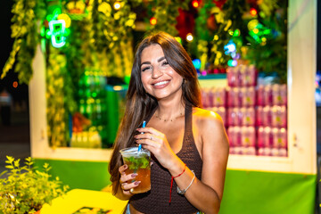 Young woman enjoying a refreshing mojito at a vibrant night market