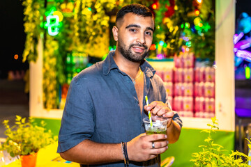 Young man enjoying refreshing mojito at night market