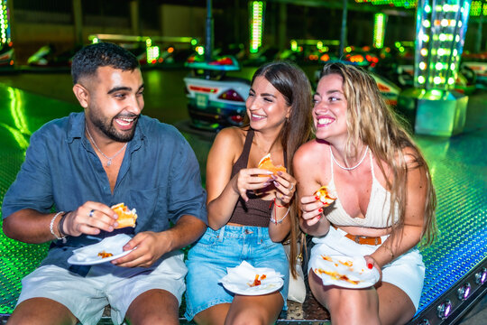 Friends eating burgers and pizza at amusement park
