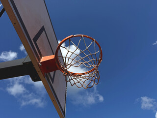 Low Angle View of Outdoor Basketball Hoop with Net against Blue Sky and Clouds on a Sunny Day