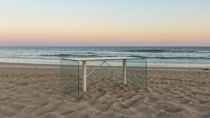 Contemporary glass table on sandy beach at sunset with ocean waves and pastel sky in background