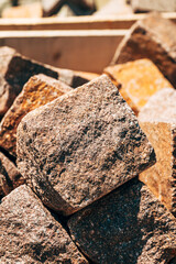 Close-up of rough stone cubes used for paving or construction, textured surfaces under sunlight