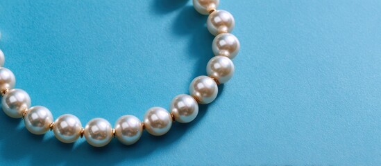 A curved string of lustrous pearls rests on a bright teal background, simple and elegant