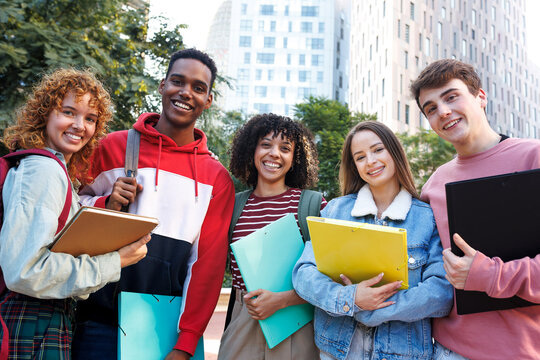 Happy university students smiling outdoors holding binders and books - Powered by Adobe