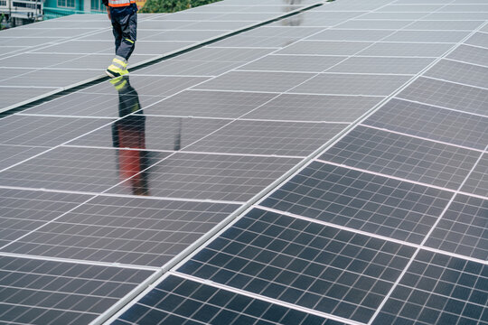 Technician walking on solar panels during maintenance in a modern urban environment on a bright day
