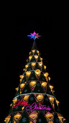 Large outdoor Christmas tree decorated with traditional conical hats and colorful lights...