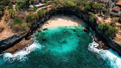 Aerial view of a secluded cove with turquoise water, a sandy beach, and rocky cliffs covered in vegetation. Waves crash against the rocks. Houses are visible on the cliff tops