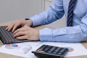 an employee in a company sits at a computer, next to a calculator, issuing invoices