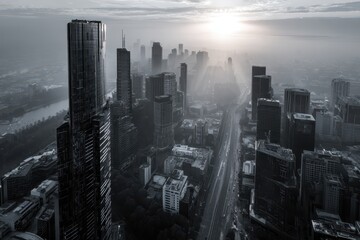 Black and white aerial view captures a sprawling cityscape at sunrise, showcasing skyscrapers and bustling streets framed by soft clouds