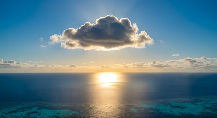 Fototapeta premium A breathtaking view of the vast ocean under a blue sky with a single cloud illuminated by the golden hour sun