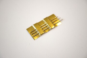 Three sewing needles stuck in gold paper on a white background with copy space, textile craft...