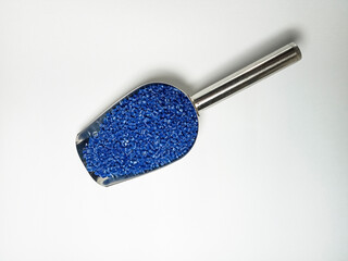 Blue plastic masterbatch, polymer carries colorful pigments with small scoops poured into a white...
