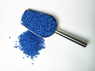 Blue plastic masterbatch, polymer carries colorful pigments with small scoops poured into a white...