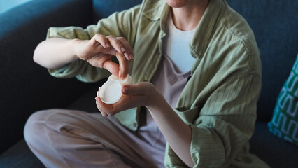The blogger opens and shows a bottle of cosmetics to her phone's camera, which is mounted on a...