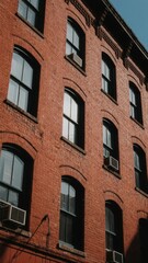 Fototapeta premium Red Brick Building with Arched Windows and Air Conditioners
